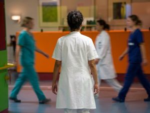 Ärztin von hinten miut Krankenhauspersonal vor einem Counter